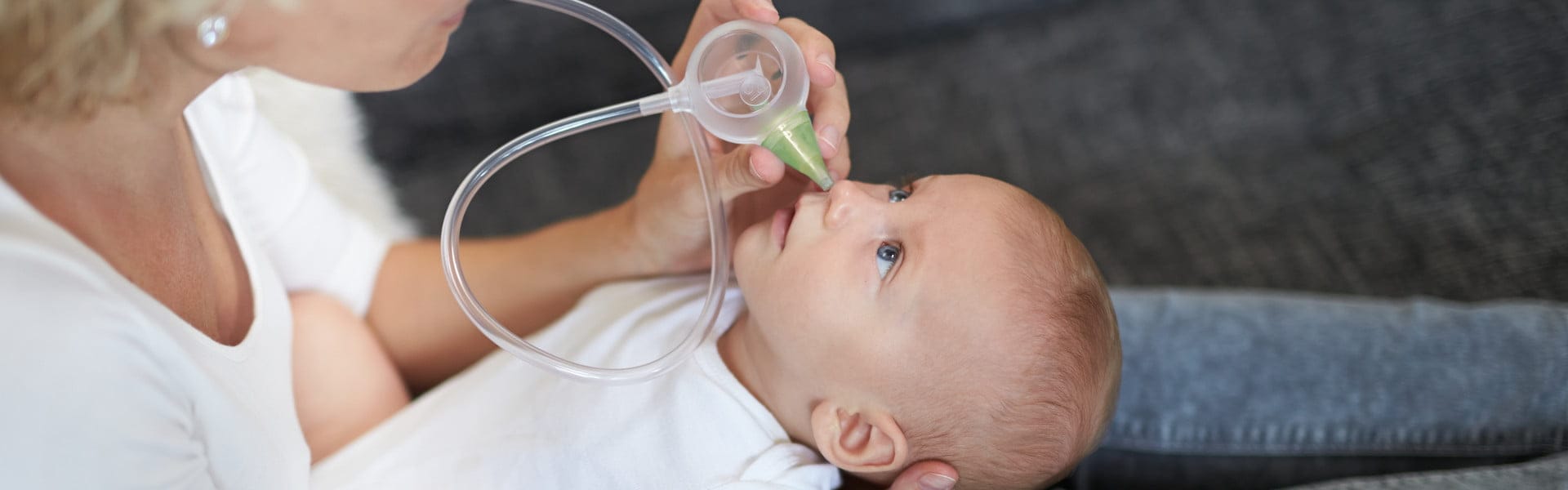 Eine Frau, die mit Hilfe des Nosiboo Eco manuellen Baby Nasensaugers die verstopfte Nase des Babys reinigt