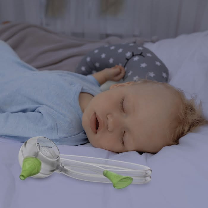 Ein Babyjunge schläft friedlich in seinem Bett neben dem Nosiboo Eco manuellen Baby Nasensauger