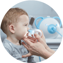Eine HNO-Ärztin reinigt die Nase eines Jungen mit Hilfe eines sicheren Baby-Nasensaugers Nosiboo Pro