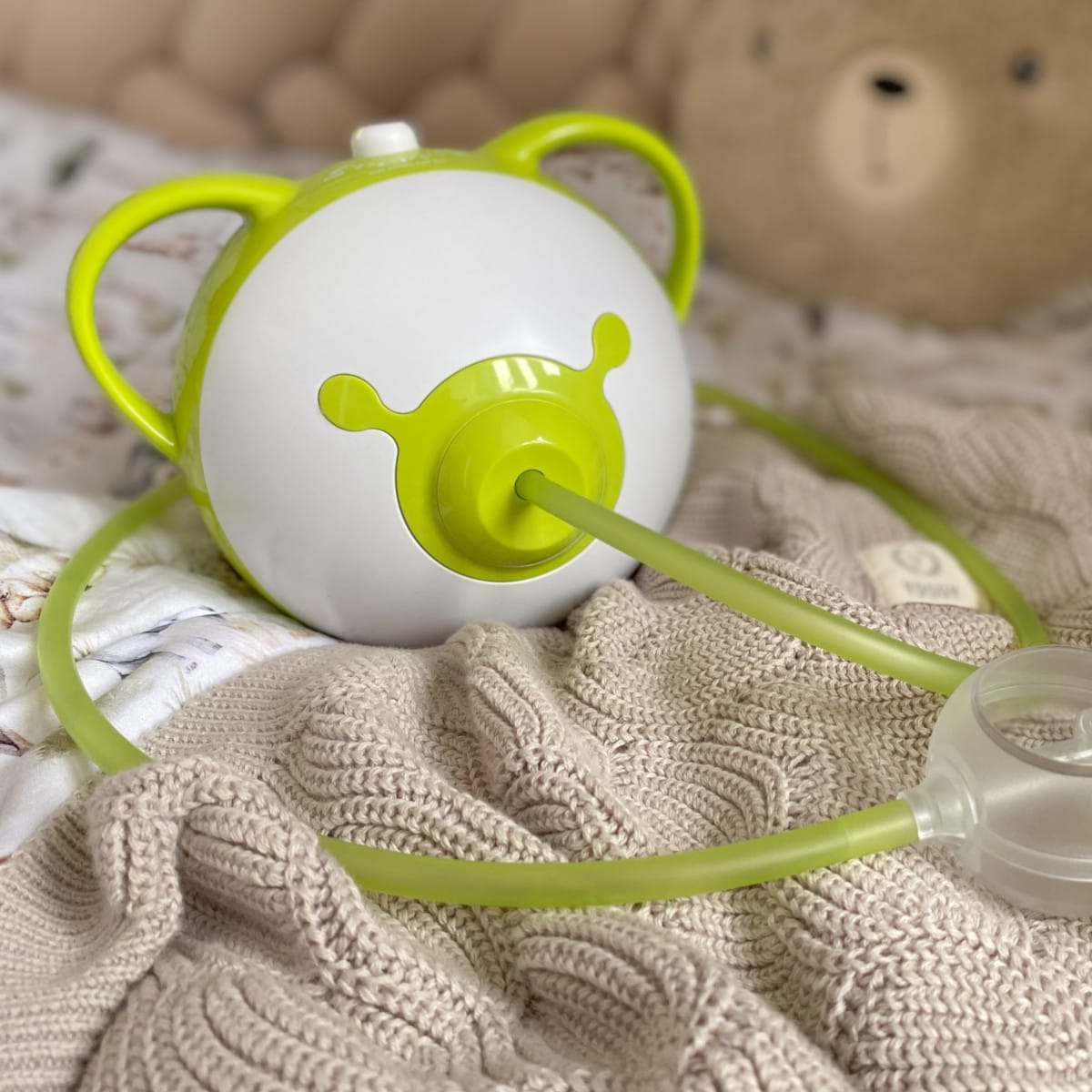 Ein grüner Nosiboo Pro2 Nasensauger auf einem Bett.